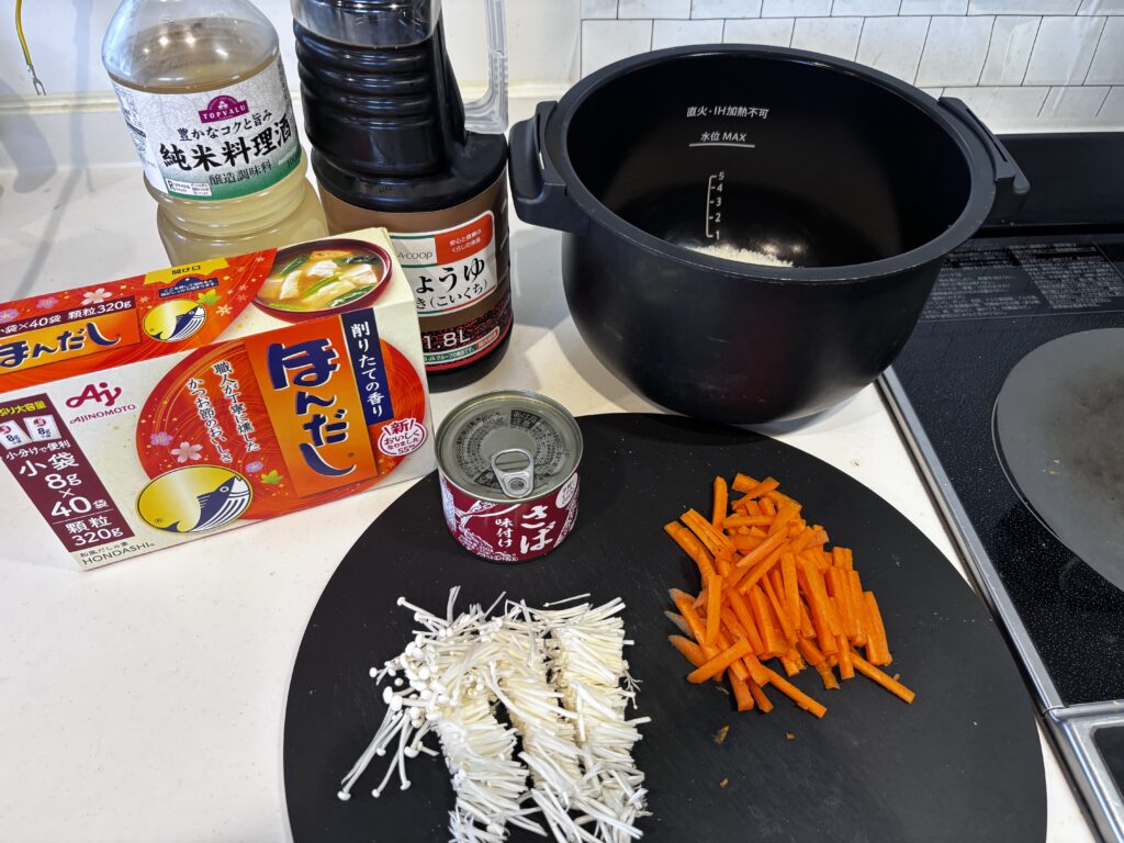 ホットクックで作るサバ缶炊き込みご飯の材料一式。サバ水煮缶、米、にんじん、しょうが、調味料を並べた様子