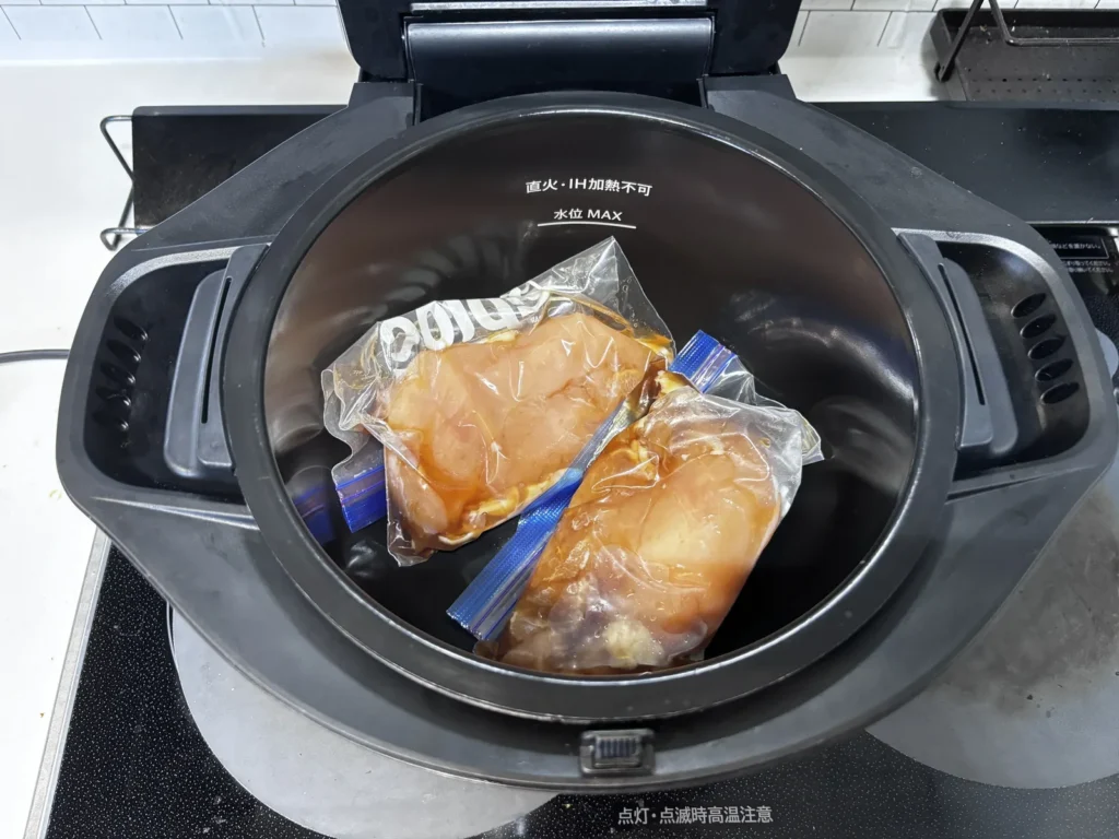 鍋の中に調味料入りジップロックで下味をつけた鶏むね肉2枚を入れた様子