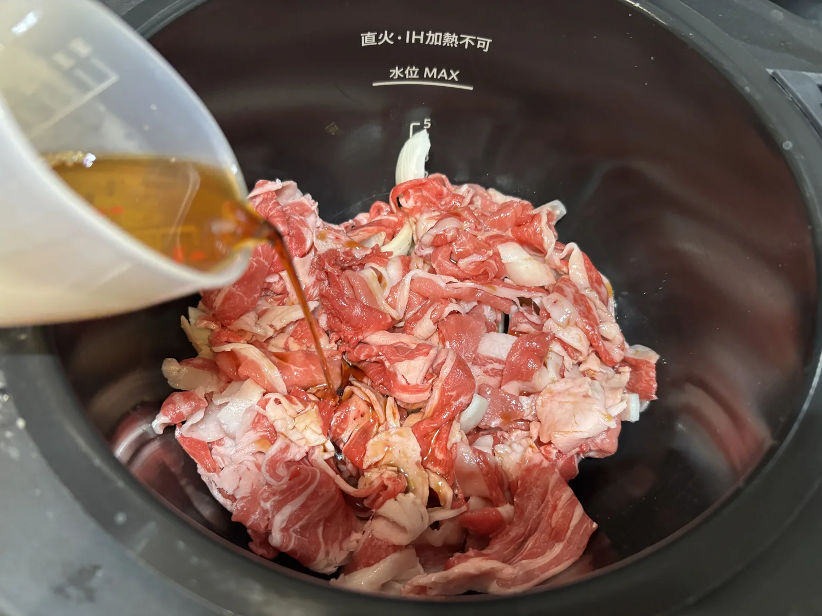 ホットクックの内鍋に牛肉と玉ねぎを入れてすき焼のたれを注ぐ
