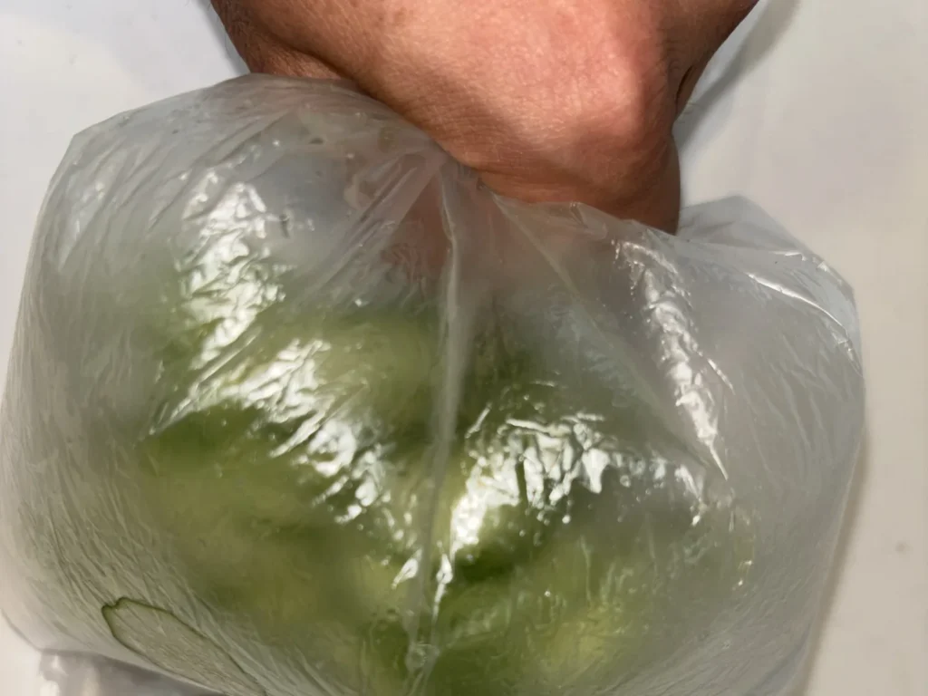 ポリ袋に入れたきゅうりを袋の上から塩もみしているところ