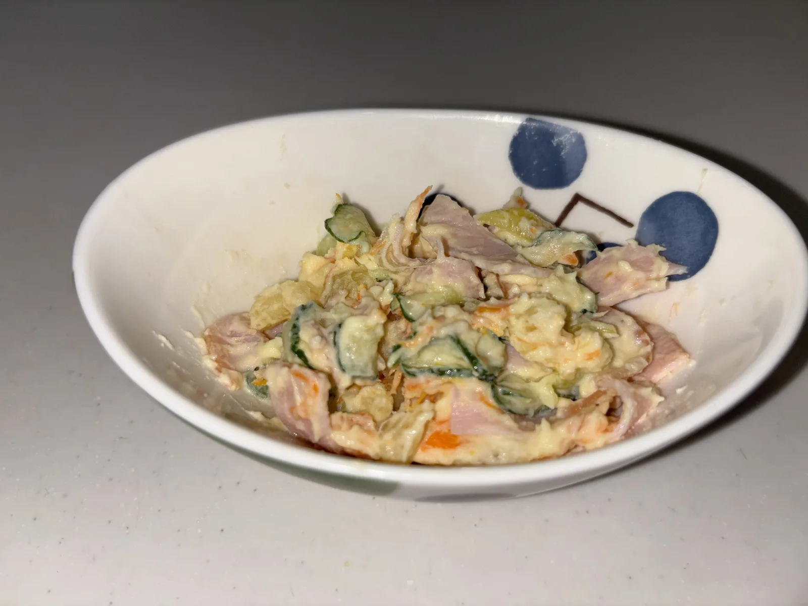 ホットクックで作ったポテトサラダを白い小皿に盛り付けたところ。つぶしたじゃがいもにハムときゅうりが混ざっている